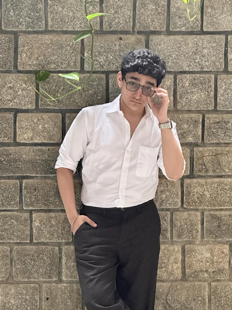 White shirt brick wall hand on glasses